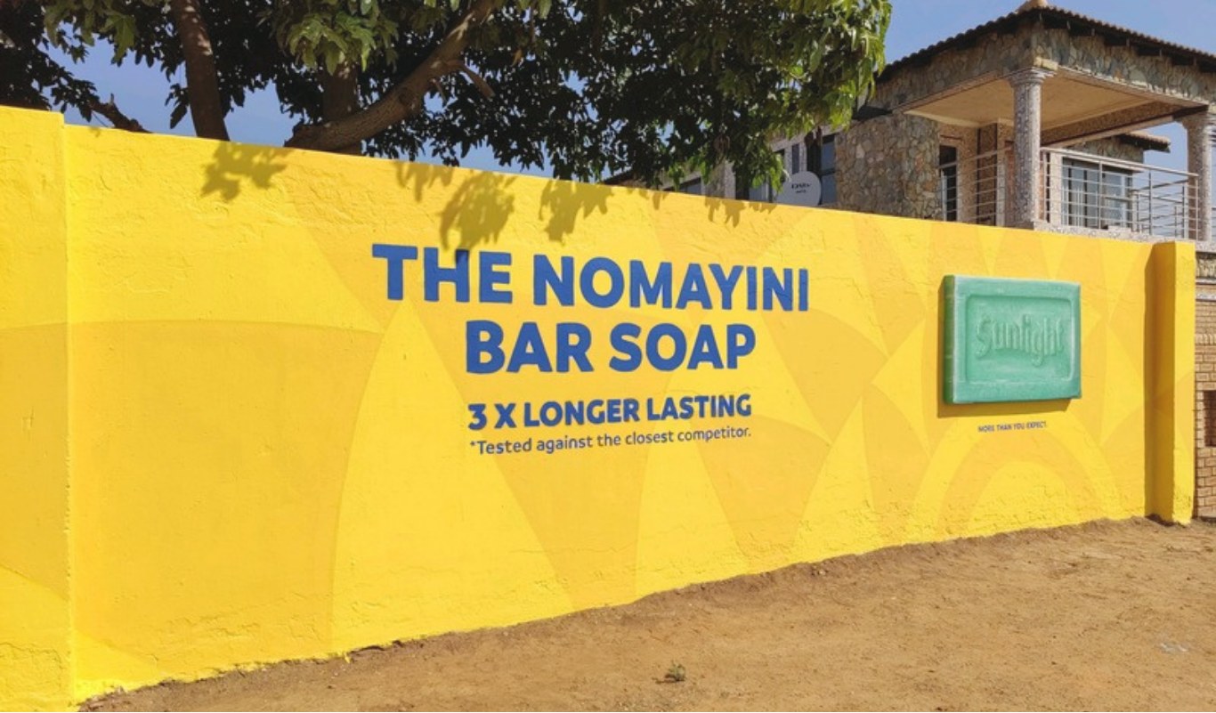 Yellow township wall painted with a bold hand-painted advertising mural